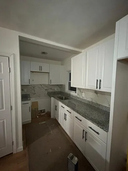 Modern kitchen remodeling featuring white shaker cabinets and gray granite countertops.